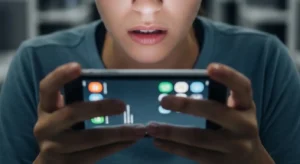 A person looking concerned at a smartphone screen with blurred data in the background.